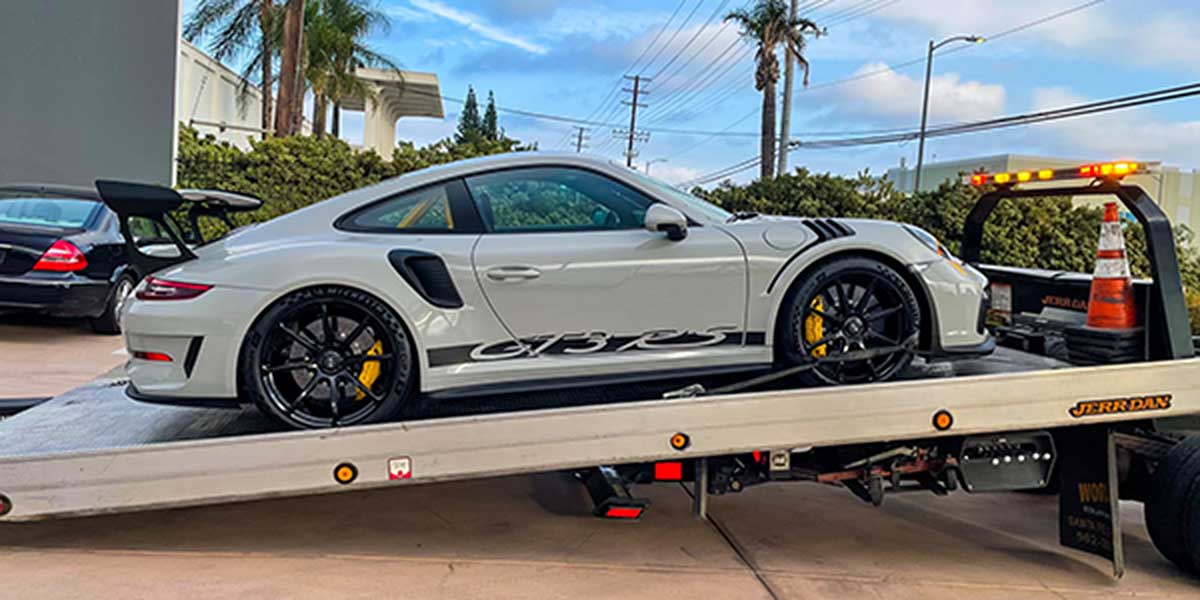 Porsche being towed by flatbed truck