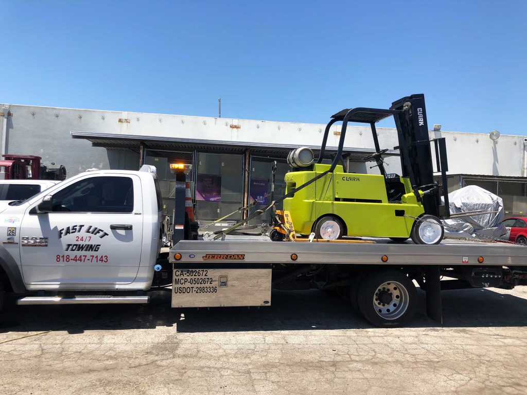 Forklift being transported on a flatbed tow truck