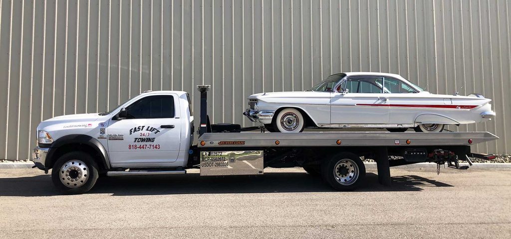 Classic car being towed long distance on a flatbed truck