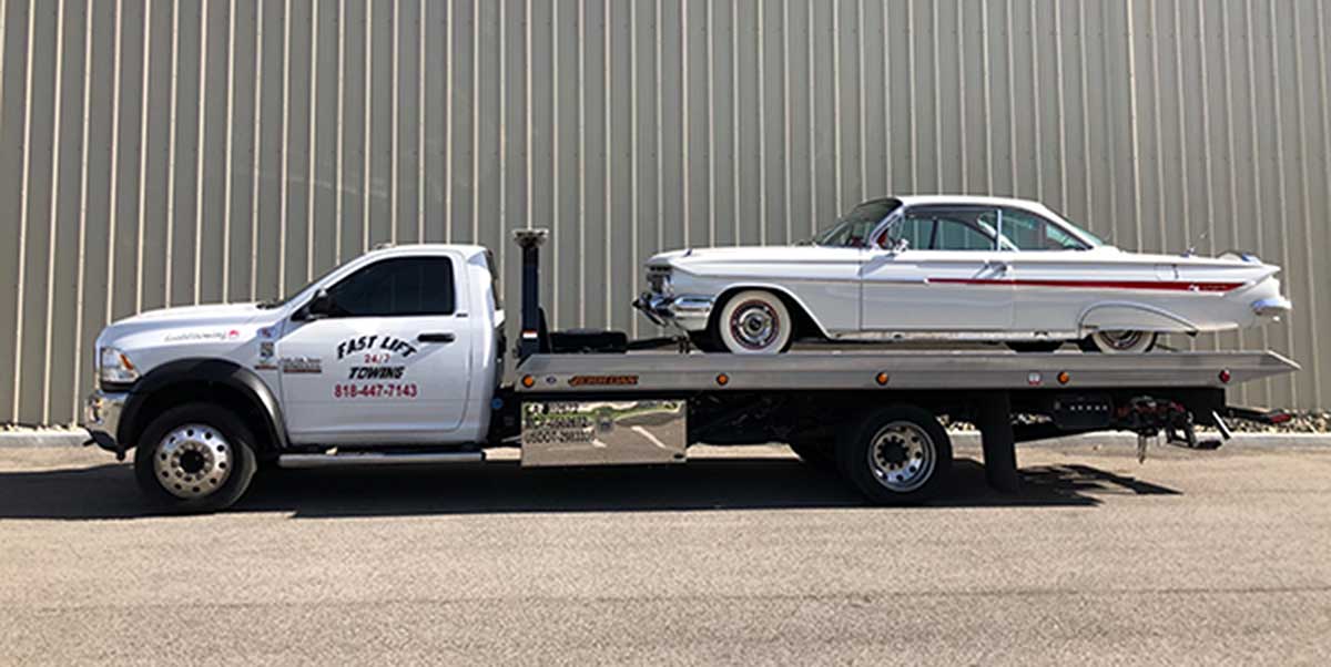 Classic car being towed long distance with flatbed tow